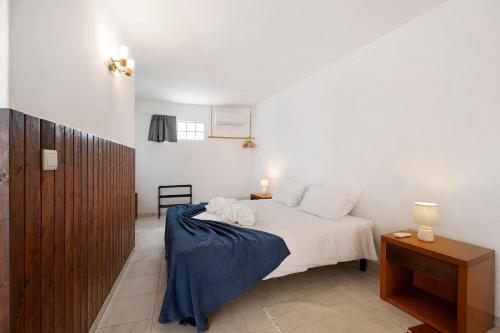 una camera da letto con un letto con lenzuola bianche e un tavolo di A Cerca - E a Lagos