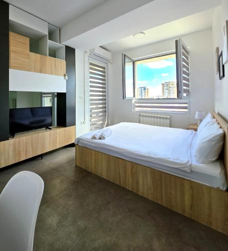 a bedroom with a large bed and a flat screen tv at Urban Serviced Apartments in Skopje