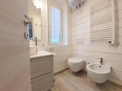 a white bathroom with a toilet and a sink at Appartamento La Perla del Golfo 2 in Capoliveri