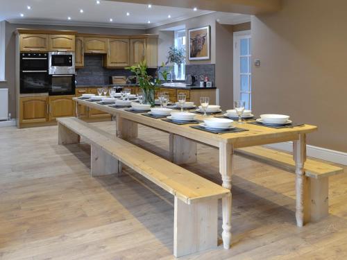 a wooden table with plates and glasses on it in a kitchen at Farmhouse in Dunragit