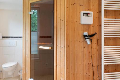 a bathroom with a wooden wall with a toilet and a shower at Friesenhof Nordsee in Wangerland