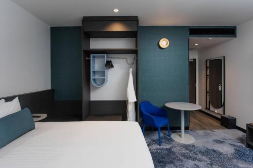 a bedroom with a bed and a table and a clock at Bayside Geelong Hotel & Apartments, an Ascend Collection Hotel in Geelong