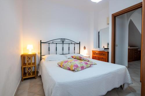 Un dormitorio con una cama blanca y un espejo. en Flower House in Villa carisciola, en Carovigno