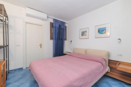 une chambre avec un lit avec une couverture rose dans l'établissement Appartamento Palau Sole, à Palau