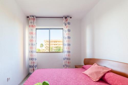 a bedroom with a pink bed and a window at Apartamento Calle Ciruelo in Aguadulce