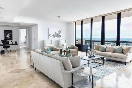 a living room with white furniture and large windows at Elegant 2 Bedroom Condo with Ocean Views in West Palm Beach