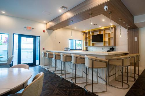 Una cocina con barra con taburetes y mesas. en DASKK Orlando Hotel near Universal Blvd, an Ascend Collection Hotel, en Orlando