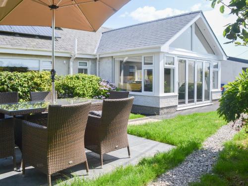 a patio with a table with chairs and an umbrella at Benlli in Aberdaron