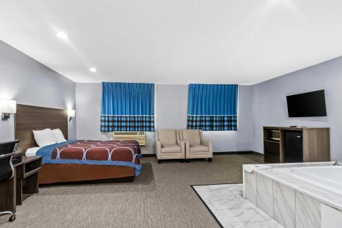 a hotel room with a bed and a tv and a tub at Rodeway Inn Delmont in Delmont
