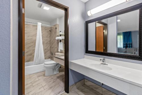 a bathroom with a sink and a toilet and a mirror at Rodeway Inn Delmont in Delmont