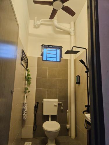 ein Bad mit einem WC und einem Deckenventilator in der Unterkunft Villa Zuhaira homestay in Kangar