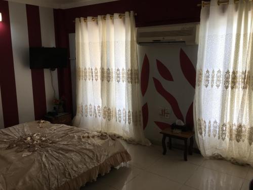 a bedroom with two white curtains and a bed at Dijlat Al Khair Hotel فندق دجلة الخير in Baghdad