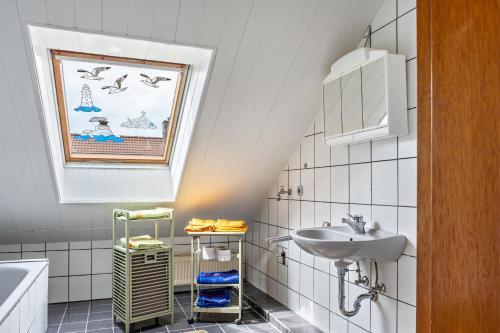 a white bathroom with a sink and a window at Ferienwohnung Klee in Fedderwarden