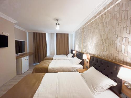 a hotel room with three beds and a tv at Helen Inn in İzmir
