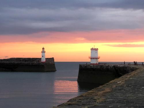 deux phares sur une jetée dans l'eau au coucher du soleil dans l'établissement Coast To Coast Cottage, à Cleator Moor