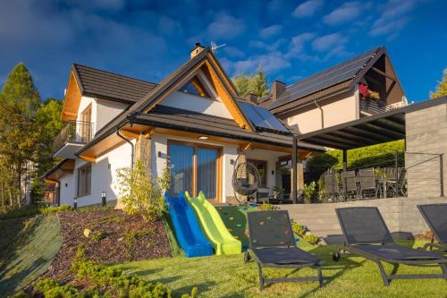 ein Haus mit einem Garten mit Stühlen und einer Rutsche in der Unterkunft Przestrony apartament z trzema sypialniami - jacuzzi i parking, kącik zabaw dla dzieci w cenie - świetny wybór dla rodzin lub grupy znajomych in Szczawnica