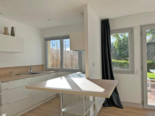 Una cocina con gabinetes blancos, una mesa y ventanas. en Au p'tit Colombier, en Hillion