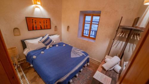 a bedroom with a bed with blue sheets and a window at Stella 1 - joli appartement en médina avec cheminée in Essaouira