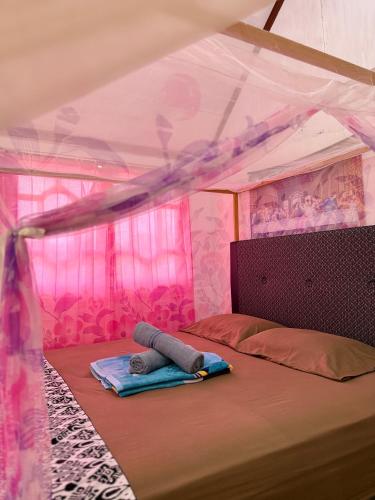 a bed in a pink room with a canopy at Novita Homestay in Bunaken