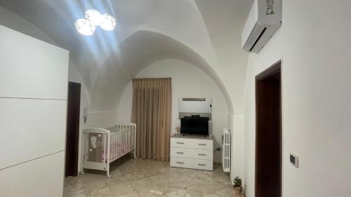 a room with a crib and a tv and a ceiling at Casa di Zia Rà in Brindisi