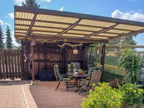 a wooden pergola with a table and chairs on a patio at Ferienwohnung Am Recknitzhang in Carlewitz