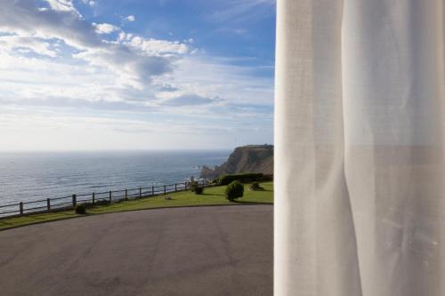 a view of the ocean from a white curtain at Casa Maravilla in Faro de Peñas