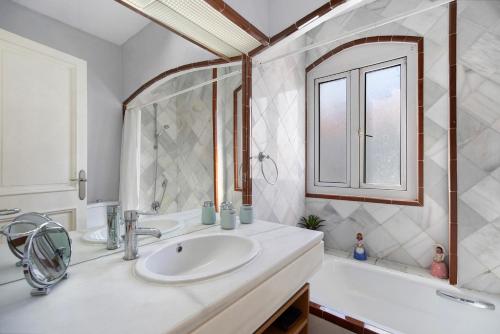 ein Badezimmer mit Waschbecken, Spiegel und Badewanne in der Unterkunft Magnifico piso en la playa in El Puerto de Santa María