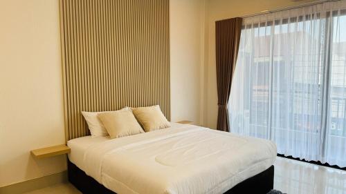 a bed in a room with a large window at Chun Pa House in Sathani Khlong Rian