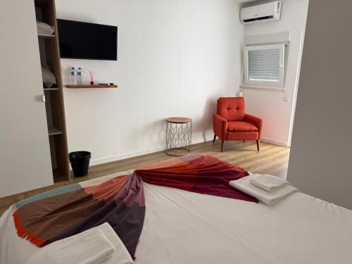 a bedroom with a bed and a red chair at 5Melros in Santiago do Cacém