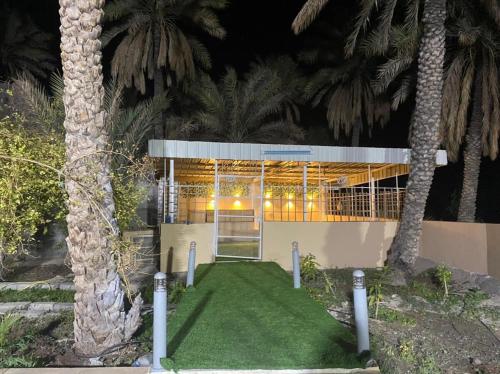 a building with palm trees in front of it at Hajir Garden House in Muşayna‘ah