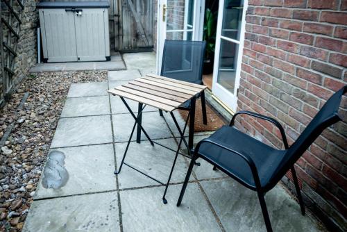 a wooden table and a chair on a patio at Avalon Sunrise our enchanting Glastonbury cottage in Glastonbury