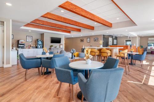 a lobby with tables and chairs and a kitchen at Casco Bay Hotel Portland Airport - Maine Mall, an Ascend Collection Hotel in South Portland