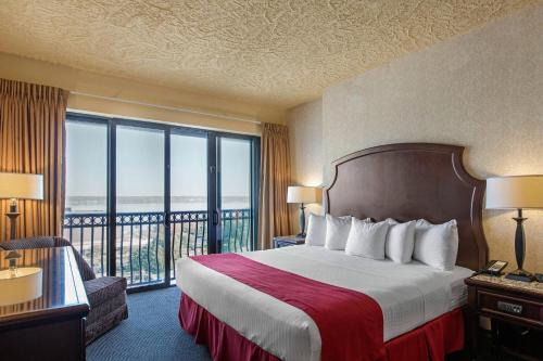 a hotel room with a bed and a balcony at Shoreline Inn & Conference Center, an Ascend Collection Hotel in Muskegon