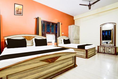 瓦拉纳西Hotel O R B Palace的卧室设有两张床铺,拥有橙色墙壁