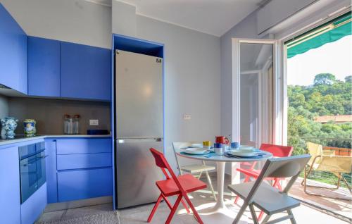 a kitchen with blue cabinets and a table with red chairs at Nice Apartment In Zoagli With Wifi in SantʼAmbrogio