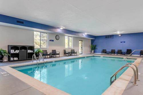 a pool in a hotel room with chairs and tables at Comfort Suites St Charles-St Louis in St. Charles