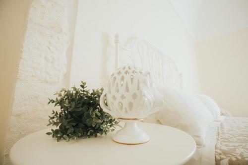 a white vase sitting on a table with a plant at Dimora Del Vicolo in Ostuni
