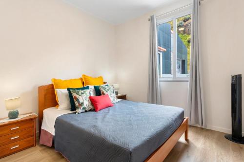 - une chambre avec un lit doté d'oreillers colorés et d'une fenêtre dans l'établissement Moradia Centro Da Cidade Funchal, à Santa Luzia