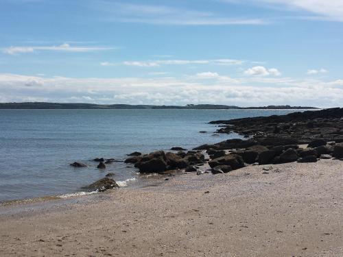 a beach with rocks and the ocean on a cloudy day at Home Farm - The Dairy -Uk34626 in Dunragit