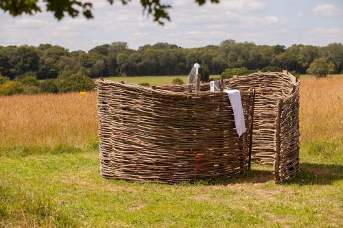 a large wicker basket sitting in the middle of a field at Simple Basketmakers Hut Cabin for Two in Chiddingstone
