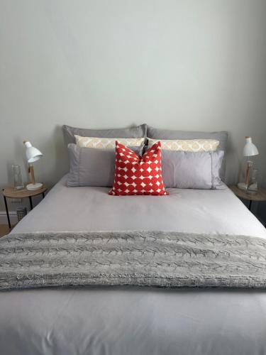 a bed with two red pillows on top of it at Island Studio Apartment in Knysna