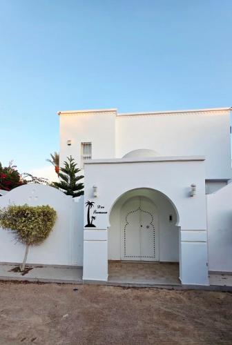 ein weißes Gebäude mit einer Tür und einem Baum in der Unterkunft dar saoussen in Triffa