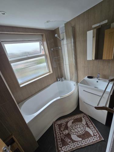 a bathroom with a tub and a toilet and a window at 4 bed house close to Allianz Stadium, LHR and London 20mins away in Hounslow