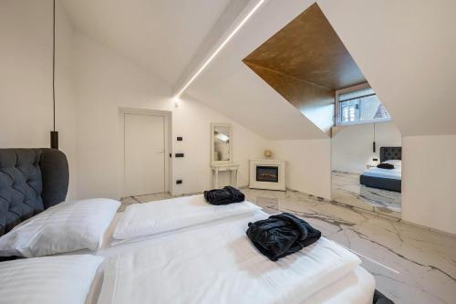 2 bedden in een witte kamer met een bank bij App 301 Palazzo Cavour in Bolzano