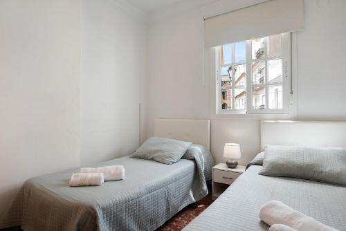 a bedroom with two beds and a window at Casa La Perla - Solo Familias in Conil de la Frontera