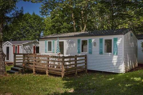 a white house with a wooden fence in the grass at Camping La Pointe du Médoc in Le Verdon-sur-Mer