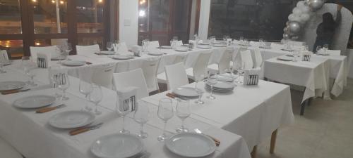 a long table with white tables with plates and wine glasses at Hostal Viví La Pampa in Santa Rosa
