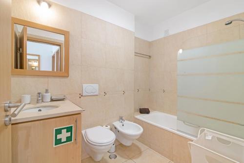 a bathroom with a toilet and a sink and a tub at Costa Cabanas 68 in Cabanas de Tavira