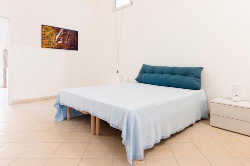 a white room with a bed with a blue pillow at Dimora Bianca in San Cesario di Lecce