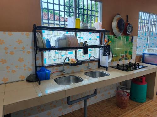 a kitchen counter with two sinks and a window at RIZQI HOMESTAY Sungai Siput with Wifi! Islamic Guest Only! in Kampong Rimba Panjang